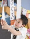 Boy Learning To Read From Hanging Paper Strip In Class