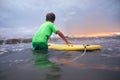 Boy learning to surf in ocean waves at sunset time Royalty Free Stock Photo