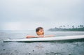 Boy learning to surf under the tropical rain Royalty Free Stock Photo