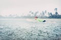 Boy learning to surf under the tropical rain Royalty Free Stock Photo