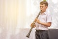 The boy learns to play the clarinet at the window. Musicology, music education and education. Royalty Free Stock Photo