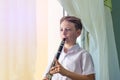 The boy learns to play the clarinet at the window. Musicology, music education and education. Royalty Free Stock Photo