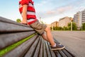 Boy legs sitting on the top of bench park relaxing