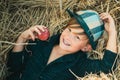 Boy lies on hay background and eats an apple. Autumn dream. Kid dreams on autumn nature. Childhood dream concept