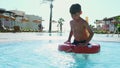 boy with lifebuoy playing in swimming pool in tropical resort slow motion