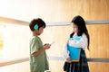 Boy is listening music and girl is holding book in hand,talking together Royalty Free Stock Photo