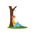 Boy listening to music, near tree in the park. Royalty Free Stock Photo