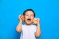 A boy listens to a shell on a blue background . Dreams of the sea. Article about vacation. Childhood. Baby and shell Royalty Free Stock Photo