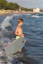 Boy with Little Surfboard on the Shoreline with Waves: Summer Vacation Concept