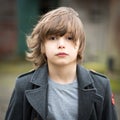 Boy in Long Coat Standing in a Farm Yard Royalty Free Stock Photo