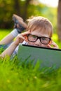 Boy looking from behind laptop in the partk Royalty Free Stock Photo