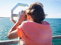 Boy is looking through a binocular at the sea Royalty Free Stock Photo