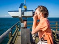 Boy is looking through a binocular at the sea Royalty Free Stock Photo