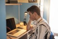 BOY LOOKING BORED AT HIS COMPUTER SCREEN