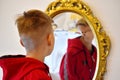 The child reflected in a distorting mirror. A fun reflection of the boy. Children`s entertainment