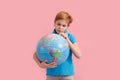 Boy looking at a globe against a pink background Royalty Free Stock Photo