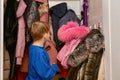 The boy is looking for his winter things in his home wardrobe before going outside Royalty Free Stock Photo