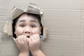 Boy looking through hole on cardboard with shocked face Royalty Free Stock Photo