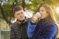 Boy looking at a Latina girl drinking coffee on the bench in a public park Royalty Free Stock Photo
