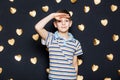 Boy looking for something on golden hearts background