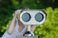 Boy looking through a tourist telescope on green Park background