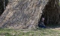 The boy looks out of the straw tent.