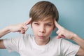 Boy looks suspiciously and holds his index fingers at his temple Royalty Free Stock Photo