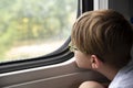 Boy looks thoughtfully out the train window. Traveling by train with children. Travel by railway Royalty Free Stock Photo