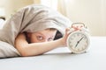 Boy lying on the bed and stopping alarm clock in morning. childs hand reaching for the alarm clock to turn it off Royalty Free Stock Photo