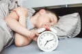 Boy lying on the bed and stopping alarm clock in morning. childs hand reaching for the alarm clock to turn it off Royalty Free Stock Photo