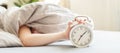 Boy lying on the bed and stopping alarm clock in morning. childs hand reaching for the alarm clock to turn it off Royalty Free Stock Photo