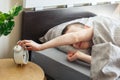 Boy lying on the bed and stopping alarm clock in morning. childs hand reaching for the alarm clock to turn it off Royalty Free Stock Photo