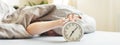 Boy lying on the bed and stopping alarm clock in morning. childs hand reaching for the alarm clock to turn it off Royalty Free Stock Photo