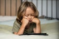 Boy lying on the bed using digital tablet computer playing games or watching cartoons at home. Royalty Free Stock Photo