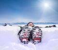 Boy lying in deep snow on the mountain hill