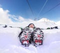 Boy lying in deep snow on the mountain hill