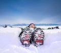 Boy lying in deep snow on the mountain hill