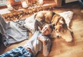 Boy lying on the floor and smiling near slipping his beagle dog on sheepskin in cozy home atmosphere. Peaceful moments of cozy