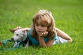 Boy lying on grass with dog. Happy puppy owner child playing with doggy on lawn.