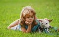 Boy lying on grass with dog. Happy puppy owner child playing with doggy on lawn.