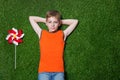 Boy lying with pinwheel on green grass Royalty Free Stock Photo