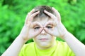 The boy made glasses around his eyes with his fingers Royalty Free Stock Photo