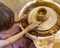 Boy makes ceramic pot on a Potter`s wheel at workshop