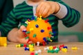 Boy makes a coronavirus layout from orange and buttons. Safety and hygiene training. Explanation of what a virus is for a child in