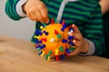 Boy makes a coronavirus layout from orange and buttons. Safety and hygiene training. Explanation of what a virus is for a child in