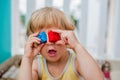 The boy makes eyes of colorful children`s blocks. Cute little kid boy with glasses playing with lots of colorful plastic blocks in