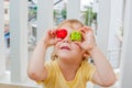 The boy makes eyes of colorful children`s blocks. Cute little kid boy with glasses playing with lots of colorful plastic