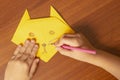 The boy makes an origami cat from a yellow sheet of paper