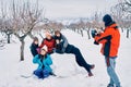 Boy makes a photo with the mobile of his family, five very happy and smiling Caucasian girls in the snow