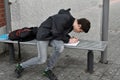 Boy makes school homework at the bus stop Royalty Free Stock Photo